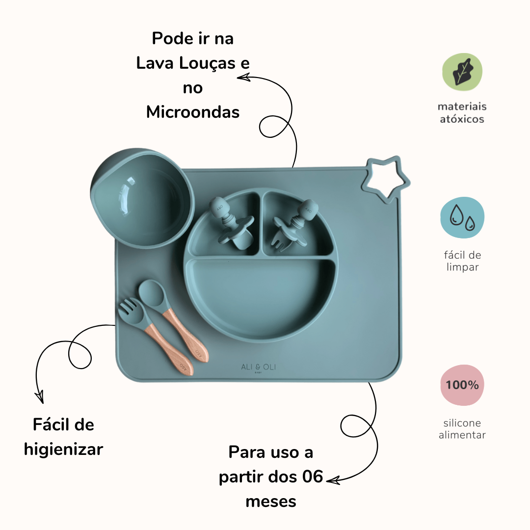 Imagem contem um Kit introdução alimentar bebê com um prato de silicone com tres divisorias sendo uma maior na horizontal e duas menores na vertical. Duas colheres pequenas para bebê de silicone com limitadores. Um jogo americano retangular com uma estrela no canto esquerdo superior e o escrito Ali & Oli Baby no centro inferior. Um bowl de silicone com ventosa e duas colheres com cabo de madeira de ponteiras de silicone. Todas as peças são na cor Verde Sage. Na imagem contem informações sobre o produto.