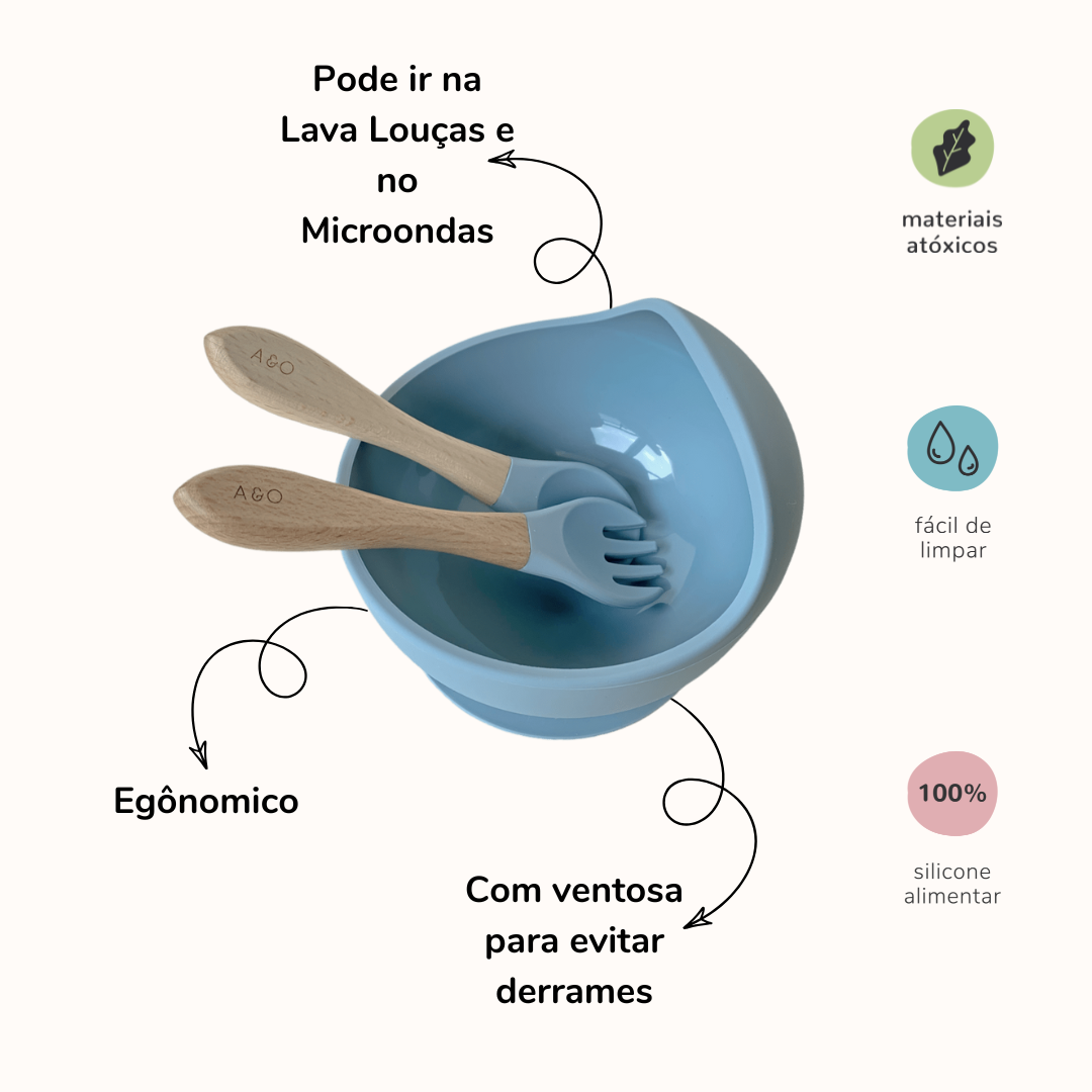 Um bowl com uma colher e um garfo com cabo de madeira e ponteira de silicone na cor azul ether. A imagem contem informações sobre o o produto.