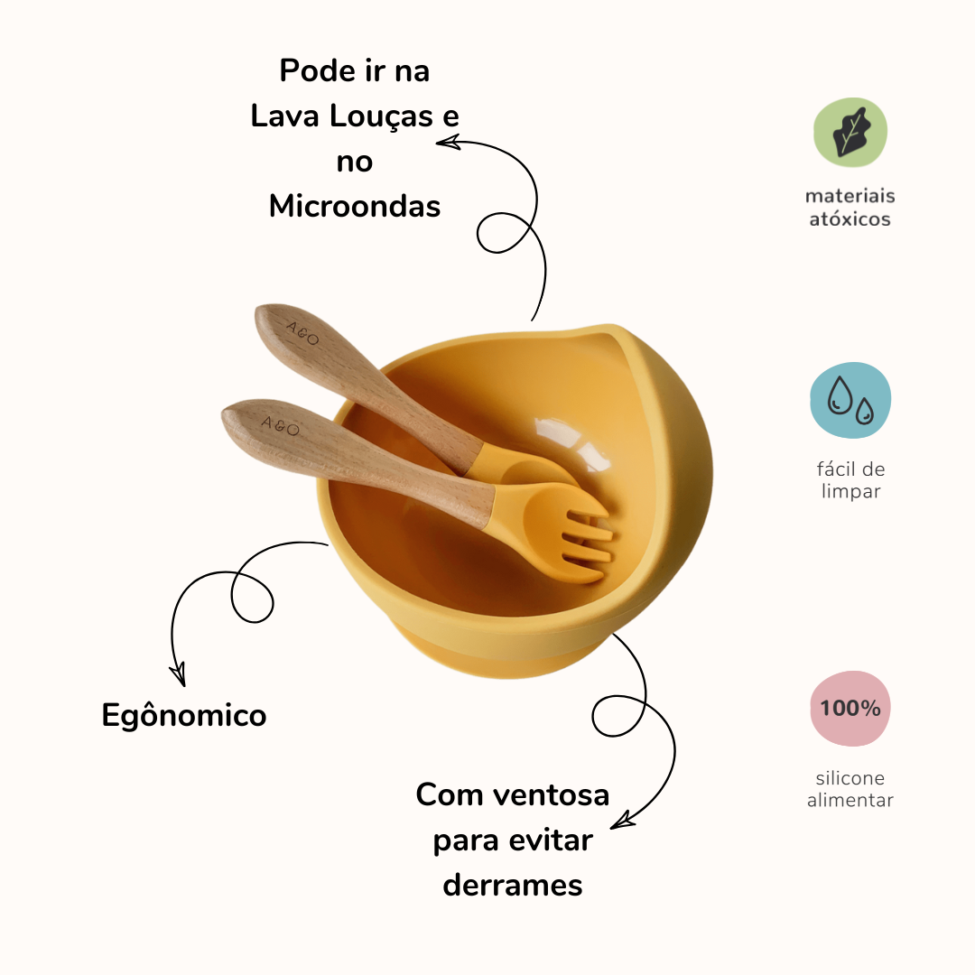 Um bowl com uma colher e um garfo com cabo de madeira e ponteira de silicone na cor amarelo mostarda. Imagem contem informações sobre o produto.