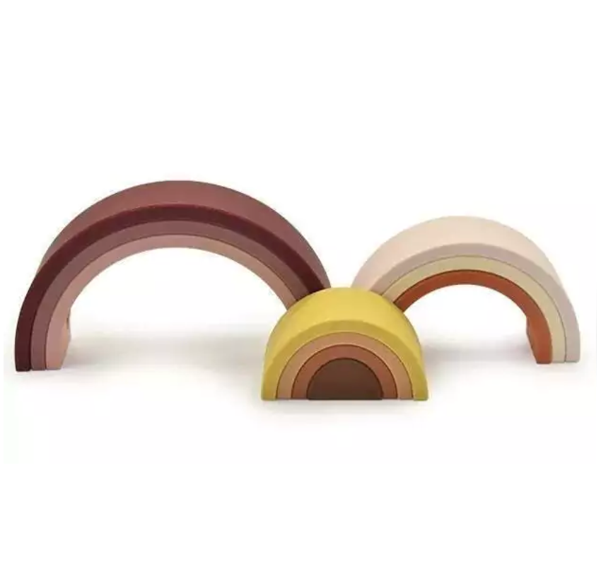 Arco-íris feito de tiras de silicone nas cores marrom, rosa, amarelo mostarda e laranja. Peças desmontáveis para brincar e empilhar e encaixar. Peças colocadas em 03 conjuntos separados para ilustrar como podem ser utilizadas.