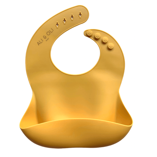 Babador de silicone com bolso cata migalha na cor amarelo mostarda.