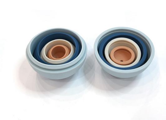 Bolas de silicone de cores variadas abertas ao meio, encaixadas, uma dentro da outra.