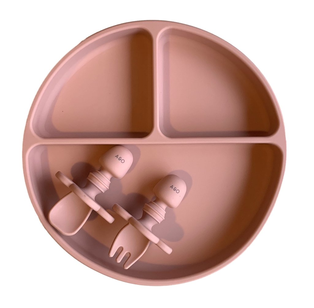 Imagem contem um prato de silicone com tres divisorias sendo uma maior na horizontal e duas menores na vertical. Duas colheres pequenas para bebê de silicone com limitadores. Todas as peças são na cor Rosa Velho.