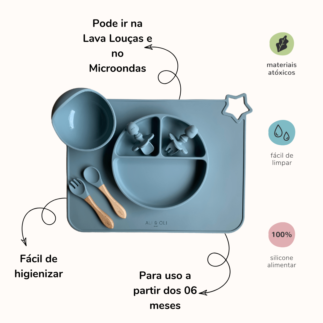 Imagem contem um Kit introdução alimentar bebê com um prato de silicone com tres divisorias sendo uma maior na horizontal e duas menores na vertical. Duas colheres pequenas para bebê de silicone com limitadores. Um jogo americano retangular com uma estrela no canto esquerdo superior e o escrito Ali & Oli Baby no centro inferior. Um bowl de silicone com ventosa e duas colheres com cabo de madeira de ponteiras de silicone. Todas as peças são na cor Azul Ether. Na imagem contem informações sobre o produto.